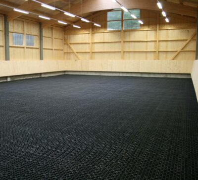 Indoor riding arena with paddock grids as separating layer